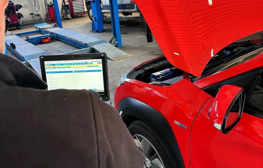 Diagnostyka komputerowa Hyundai Kona Electric w warsztacie — mechanik Bosch Car Service Przybyłowicz przy laptopie diagnostycznym, czerwona Kona z otwartą maską.